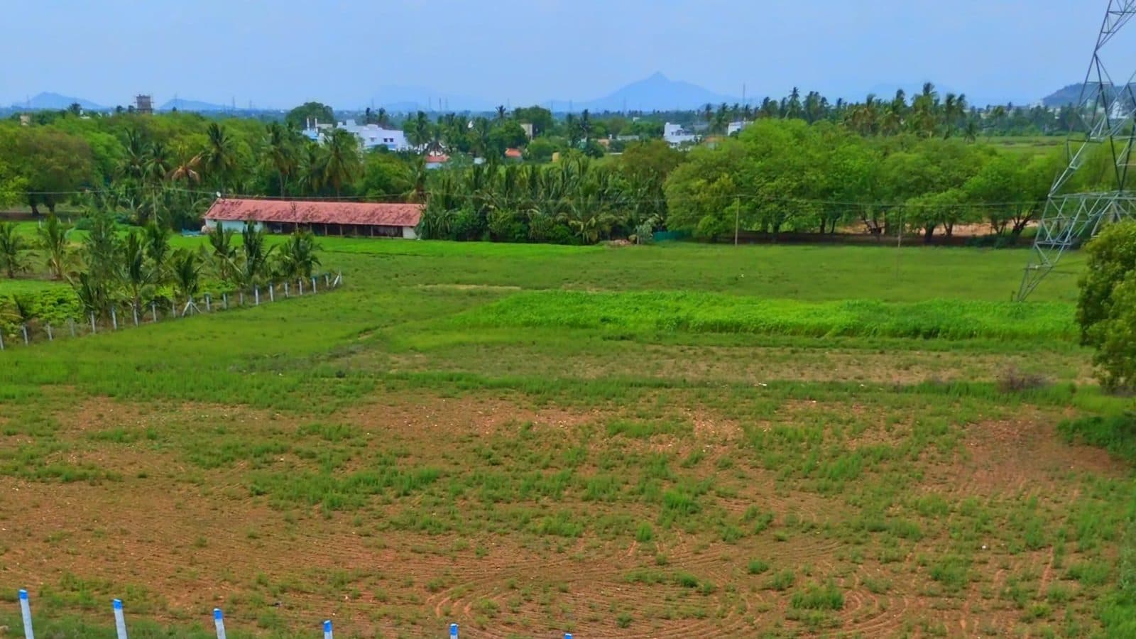 Farm land with a fence line and hills behind it in Tamil Nadu, filmed by Gmore